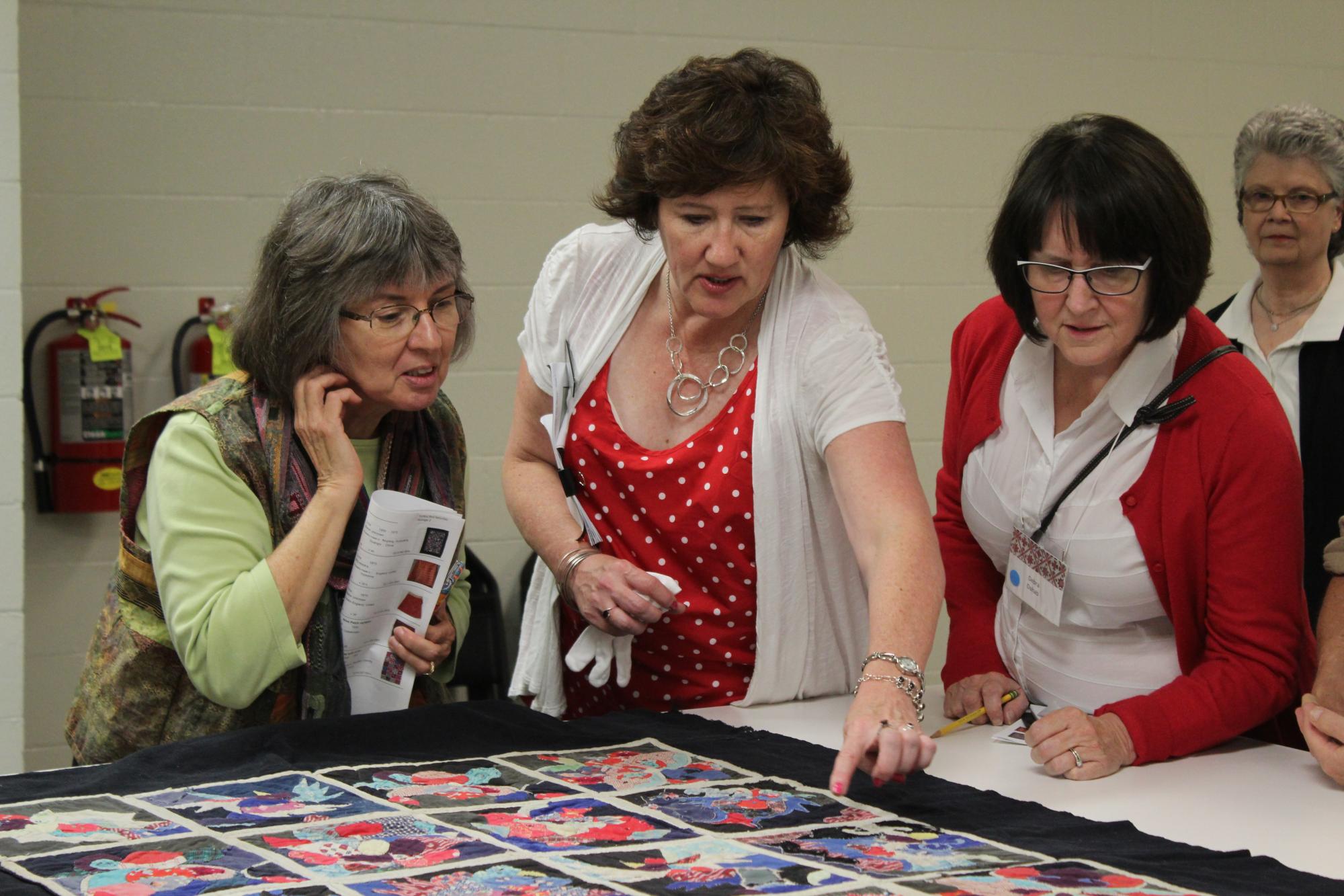 Three ladies looking at quilt