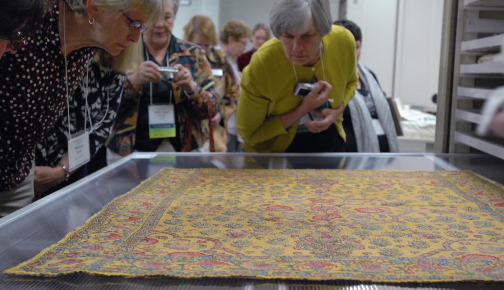 Visitors look at embroidered and quilted floor covering.