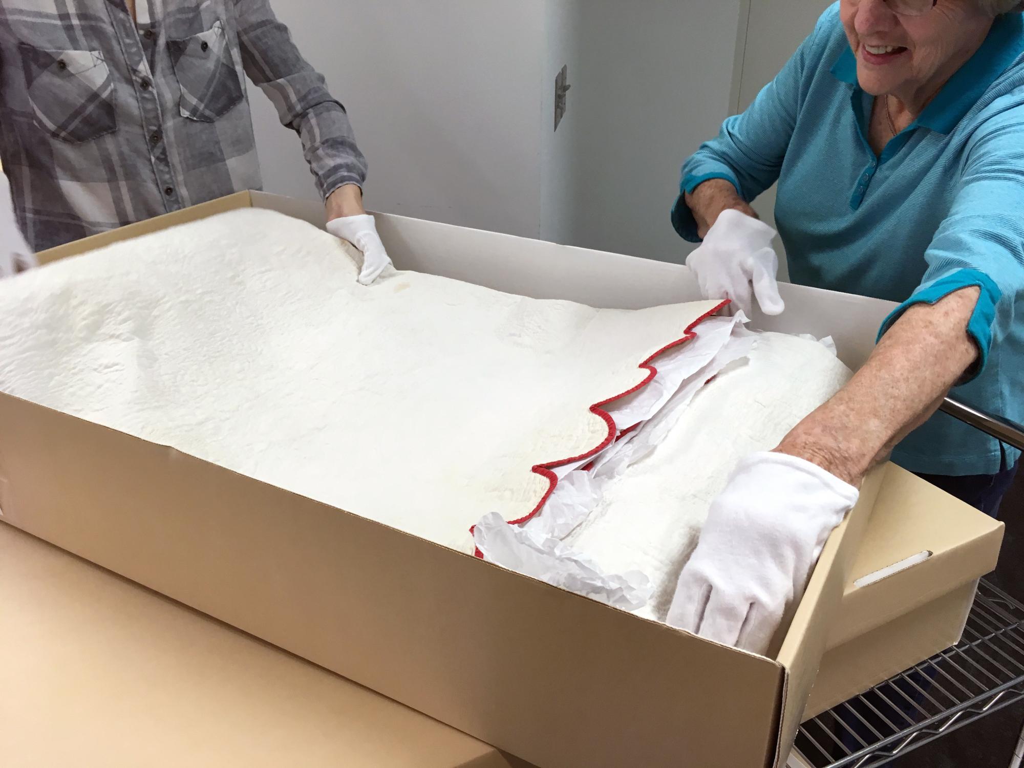 Staff carefully packaging a quilt