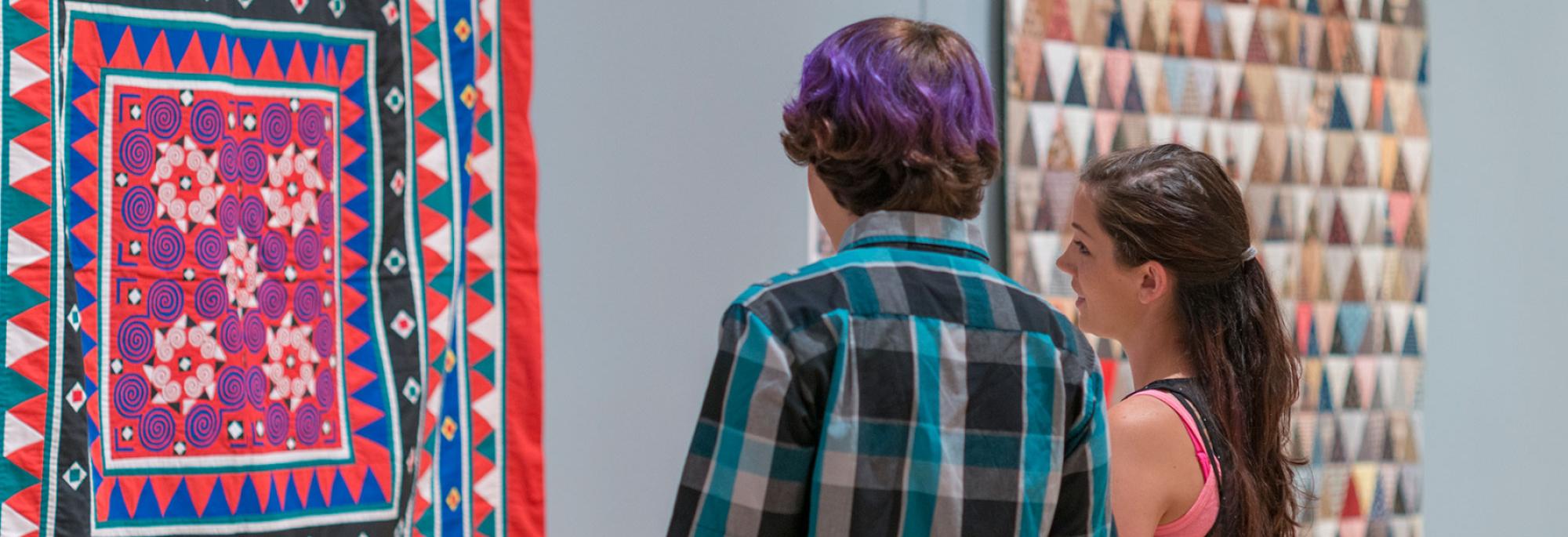 Two people look at quilts at the International Quilt Museum.
